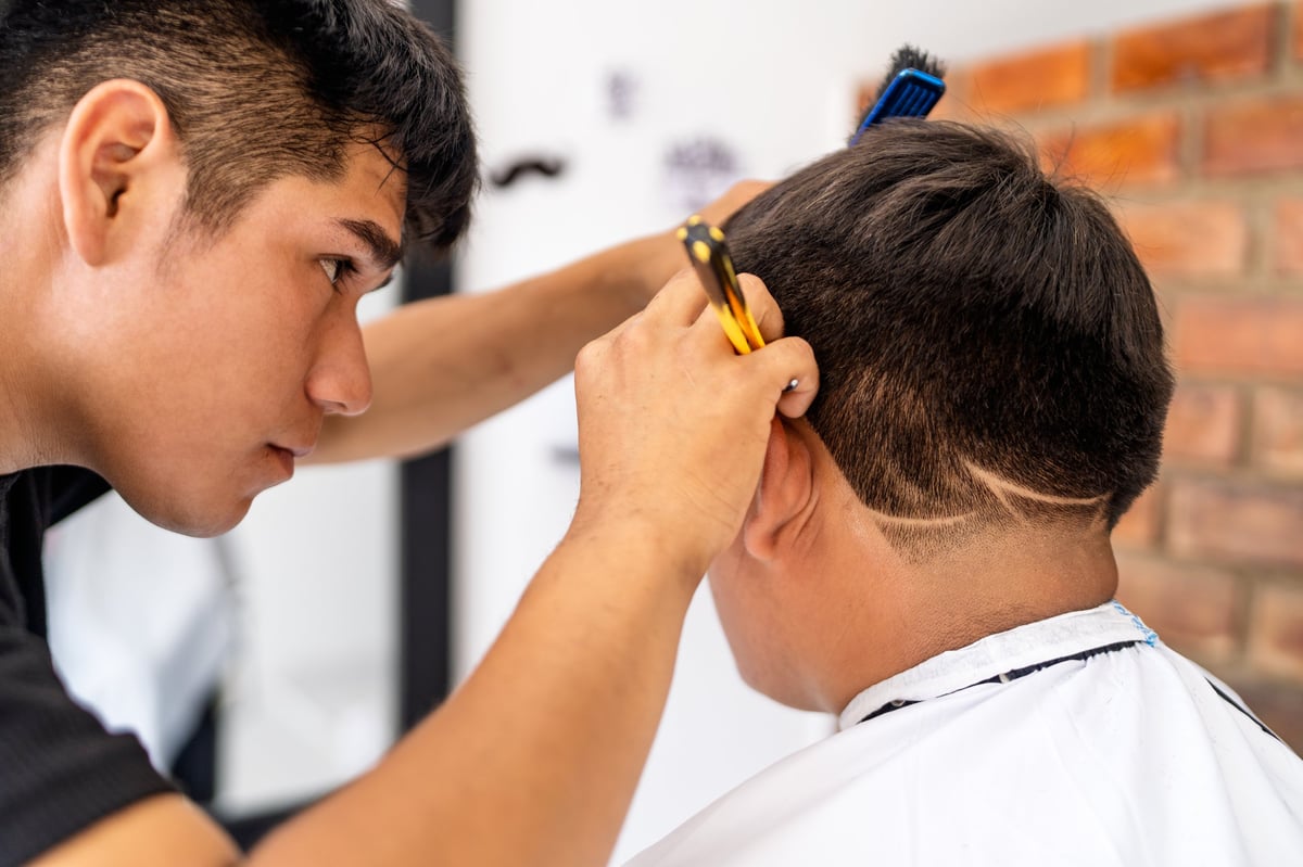 Barber styling a precise design into a younger customer's fade at Classic Cutz